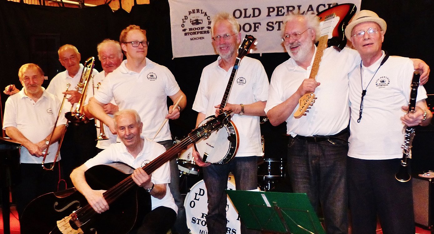 Acht Musiker in weissen Shirts und dunklen Hosen mit Instrumenten auf Bühne