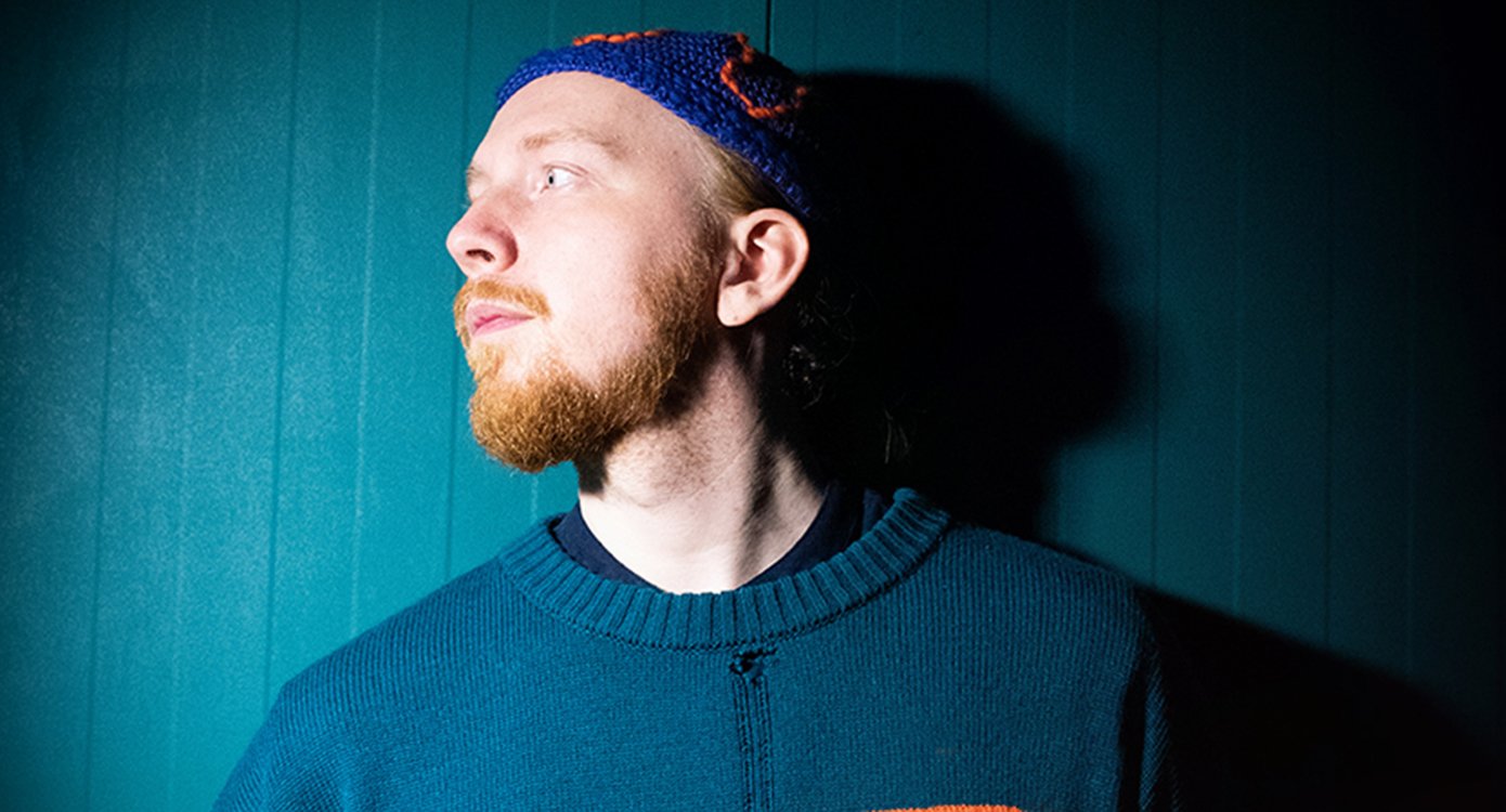 ein Bild des Künstlers im Profil mit einer Mütze auf blauem Hintergrund