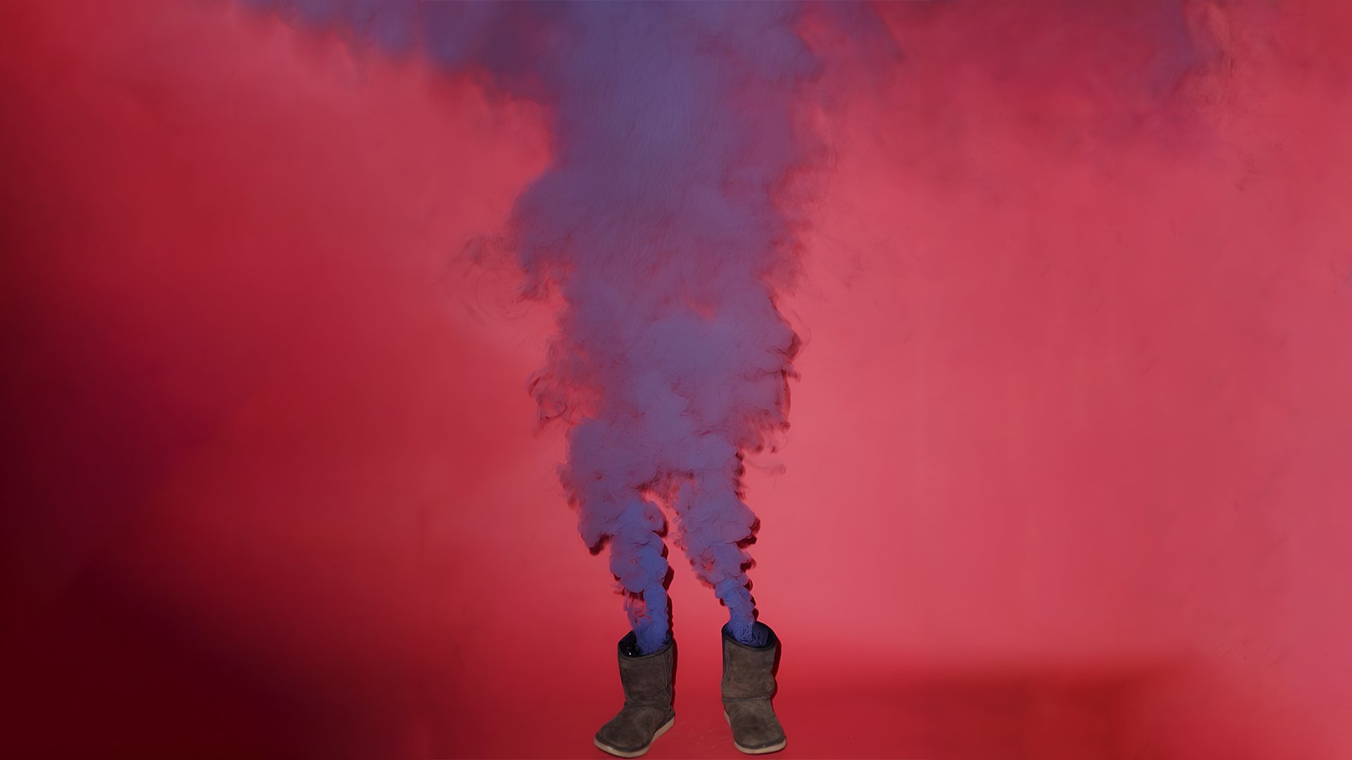 Lila Nebel kommt aus zwei braunen Stiefeln vor rotem Hintergrund