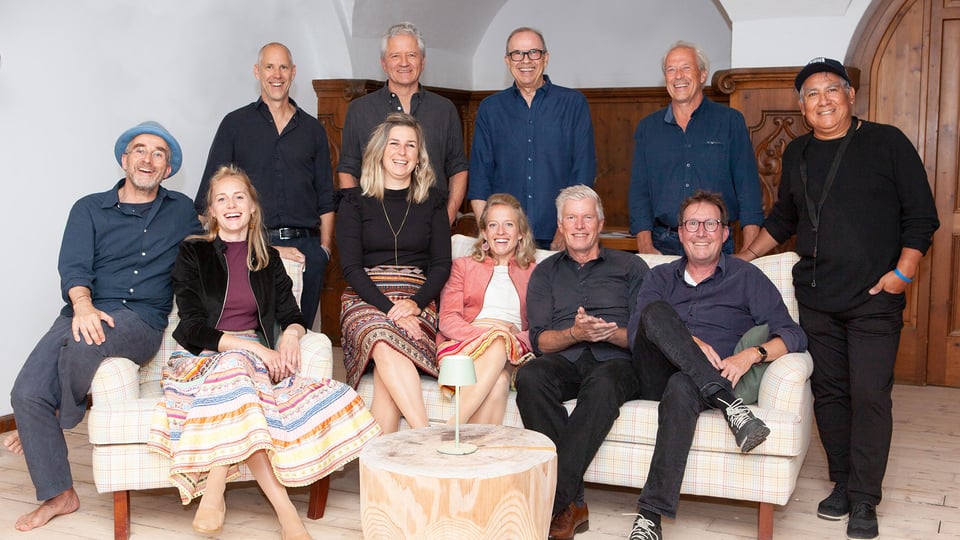 Foto für die Veranstaltung „Schlierseer Bauerntheater: Perlseer & Trovasur“ mit einer Gruppe von Personen sitzend rund um ein weißes Sofa.