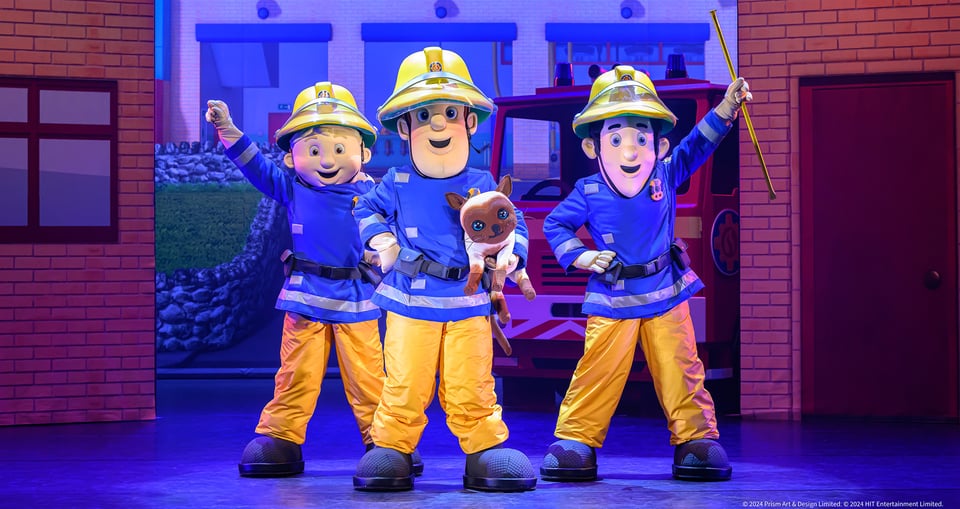 Drei Personen in Feuerwehrkostümen während eines Kindertheaterstücks