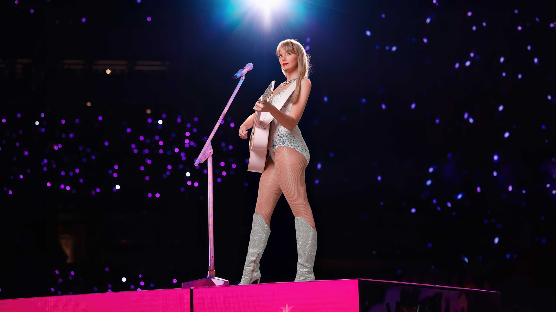 Foto für die Veranstaltung LOVER – A Tribute to Taylor Swift by Charity Eden mit der Künstlerin auf der Bühne mit Gitarre und Mikrofon.