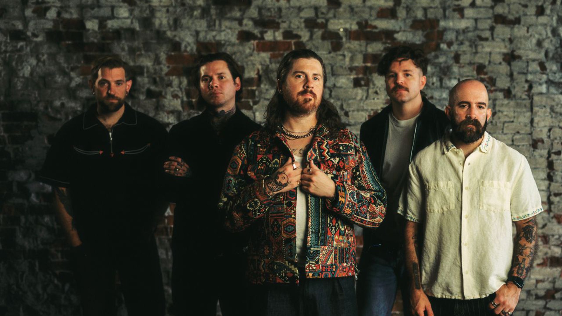 Die fünf Bandmitglieder vor einer grauen Mauer