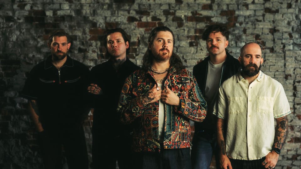 Die fünf Bandmitglieder vor einer grauen Mauer