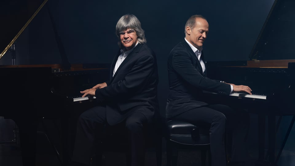 Zwei Herren Rücken an Rücken an zwei Konzertflügeln sitzend