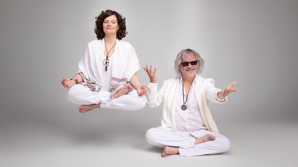 Foto für die Veranstaltung von Petzenhauser & Wählt, beide in Weiß gekleidet, in Yogaposition vor hellem Hintergrund.