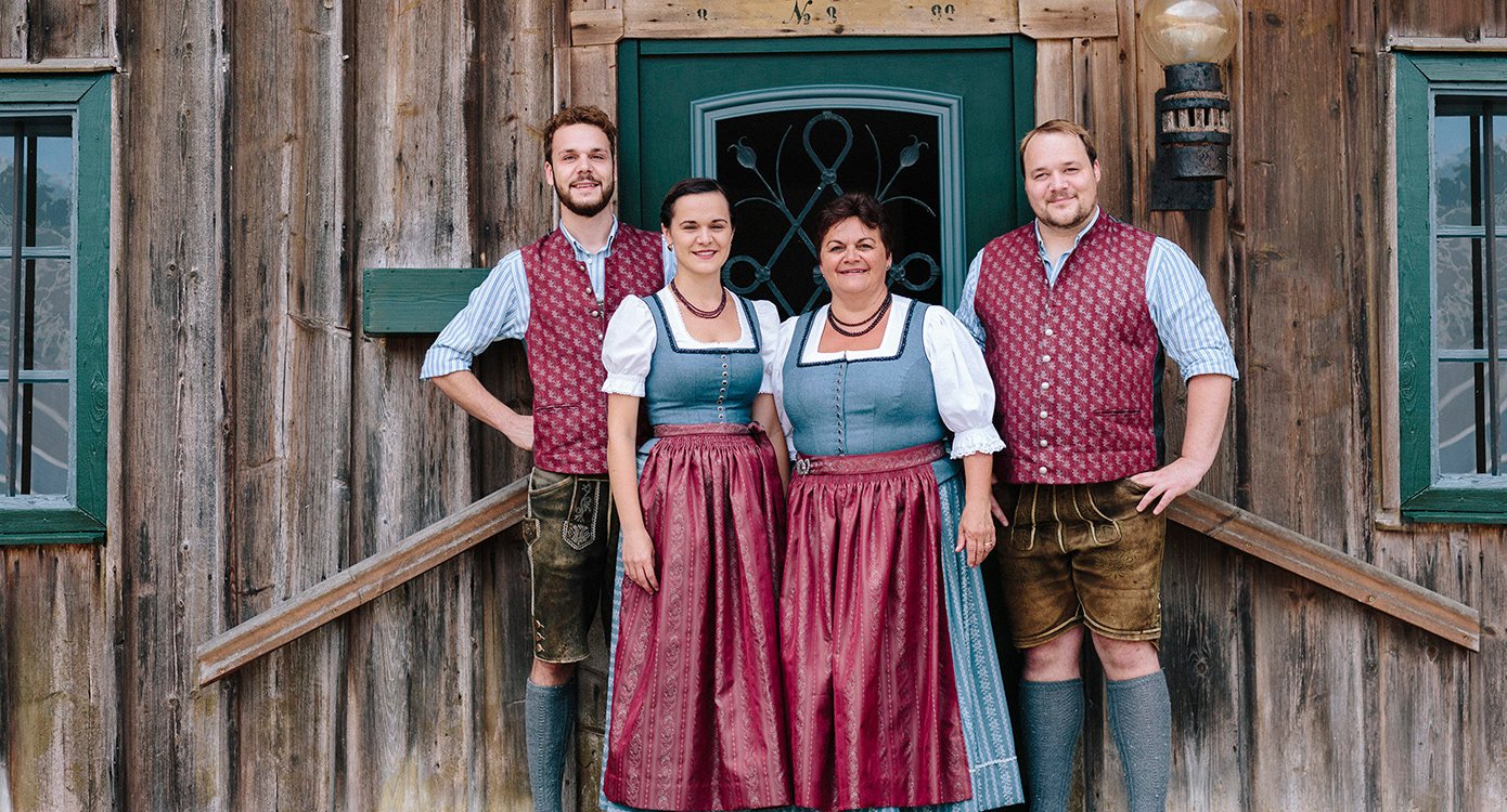 Vier Künstler in Tracht vor einer rustikalen Holzwand