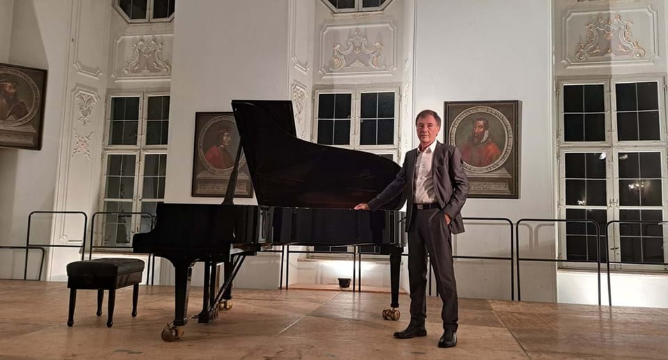 Mann in festlichem Saal an Konzertflügel stehend