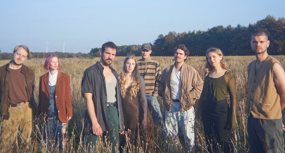 eine Gruppe von Jungen und Mädchen in der Mitte einer Wiese mit blauem Himmel