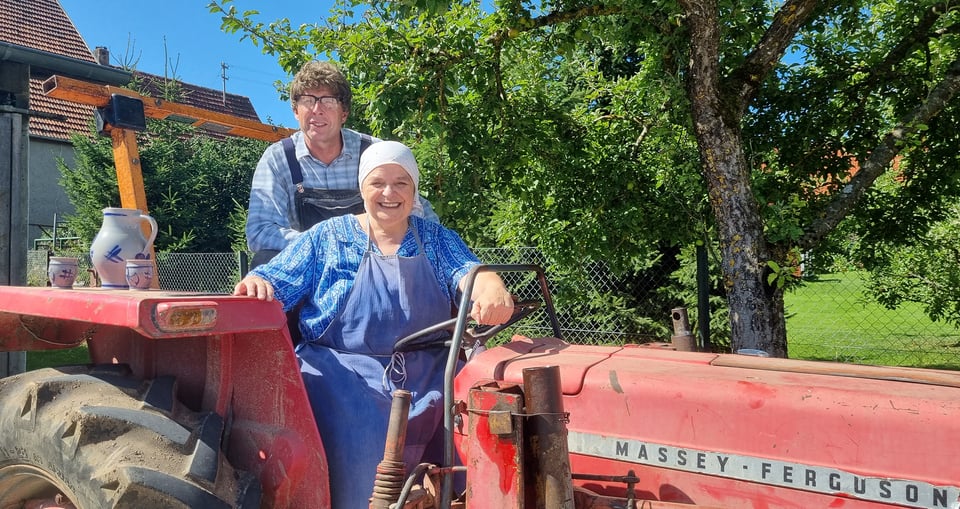 eine Frau und ein Mann sitzen auf einem Traktor auf dem Feld
