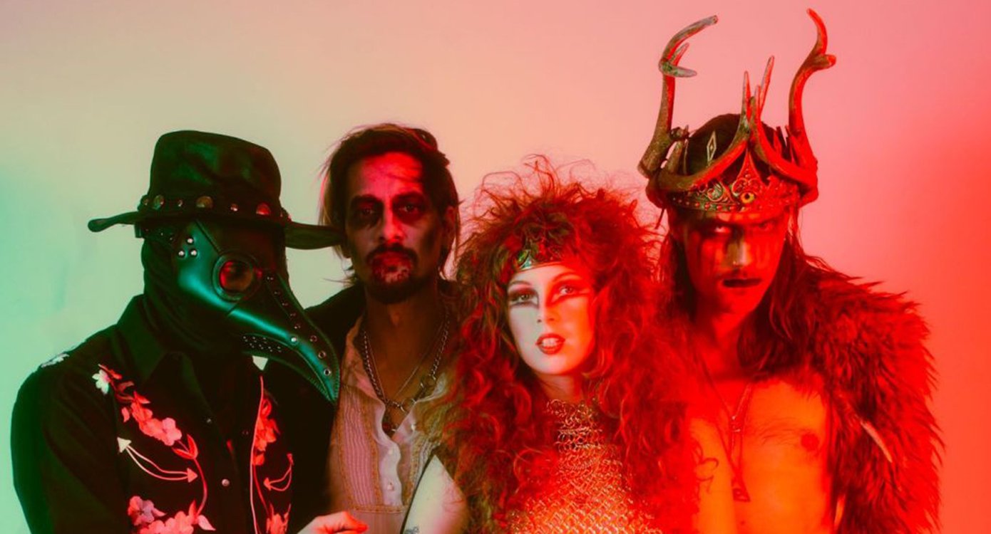 die Musikgruppe „castle rat“, bestehend aus vier Personen, einem Mädchen, zwei Jungen und einer weiteren Person mit einer Maske. Sie sind kostümiert, das Foto hat viele Rottöne.
