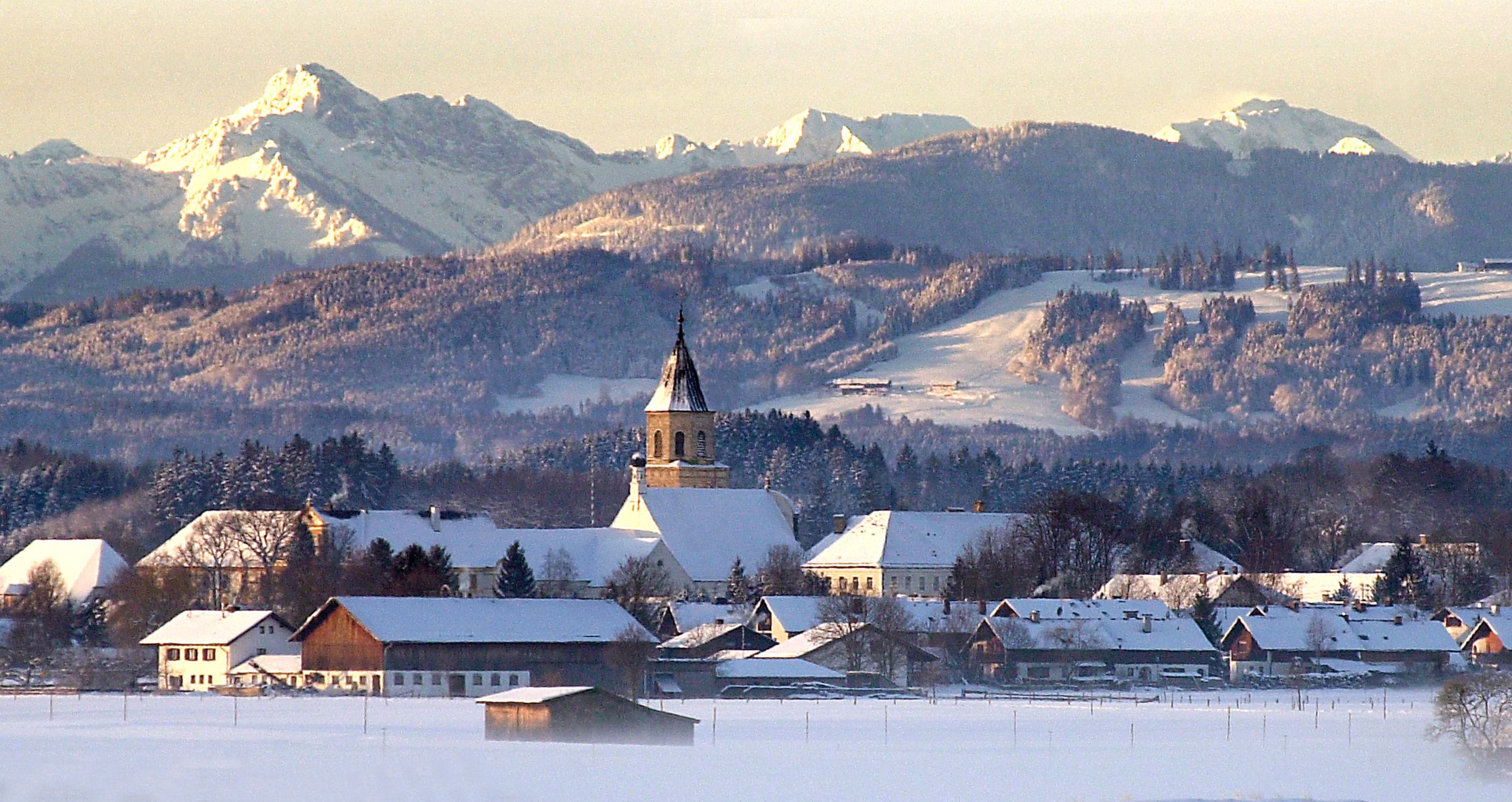 Gebirgslandschaft mit schneebedeckten Häusern und Kirchturm