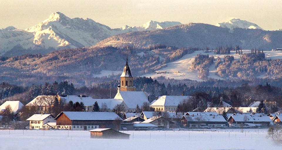 Gebirgslandschaft mit schneebedeckten Häusern und Kirchturm