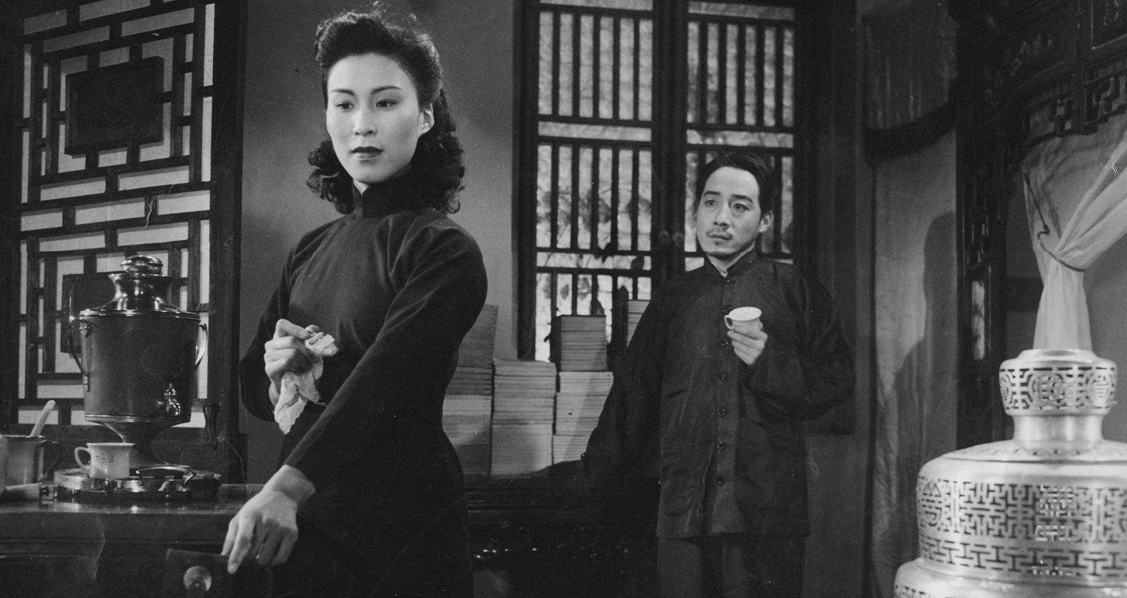 schwarz weiss Bild von zwei Darstellern in einem Raum mit chinesischer Einrichtung