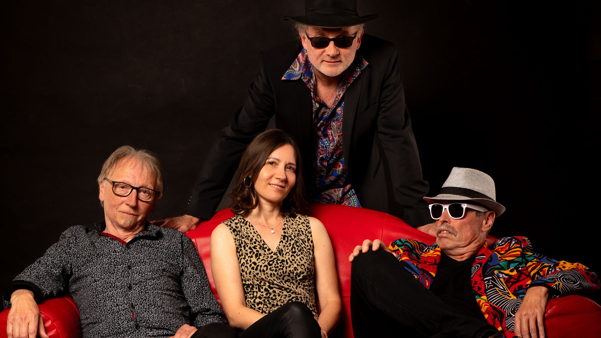 Foto vom Event Yvonne Isegrei & Band mit den Künstlern: Drei sitzen auf einem roten Sofa, einer steht dahinter