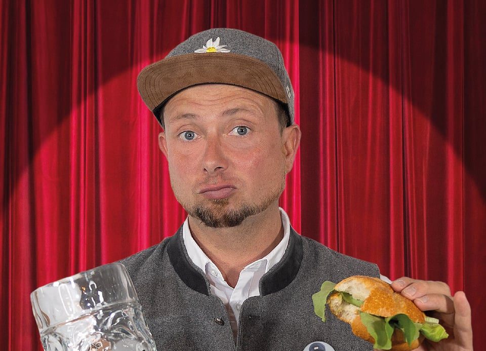 Foto des Künstlers mit einem Bier und einem Semmel, im Hintergrund rote Vorhänge.