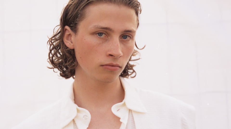 Portrait des Künstlers in weißem Hemd vor weißem Hintergrund