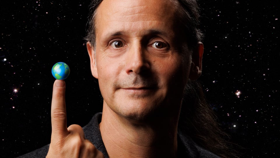 Foto für das Event Philipp Weber – POWER TO THE POPEL mit dem Künstler, der die Erdkugel auf dem Zeigefinger balanciert, vor einem sternenklaren Nachthimmel.