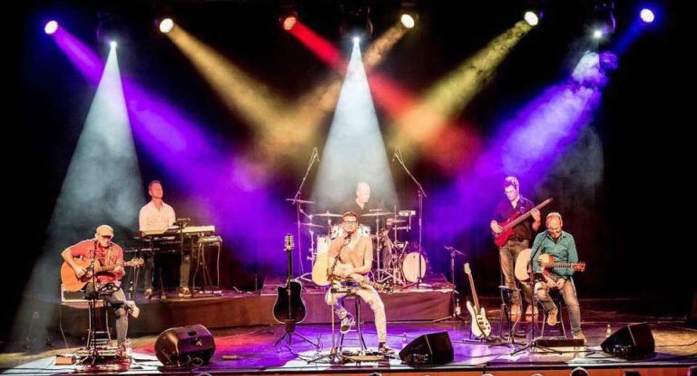 die Band „Auf A Wort“ bei einem Konzert auf der Bühne mit farbigen Glühbirnen.