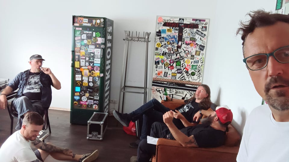 Ein Bild der Band in einem Raum mit Möbeln mit bunten Aufklebern