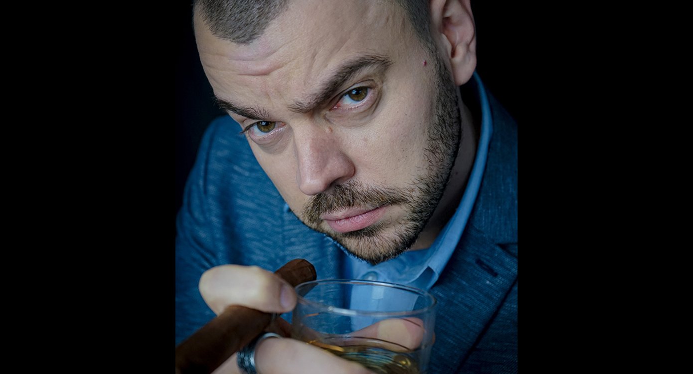 Foto des Gesichts eines Mannes mit einem Glas und einer Zigarre in der Hand auf schwarzem Hintergrund