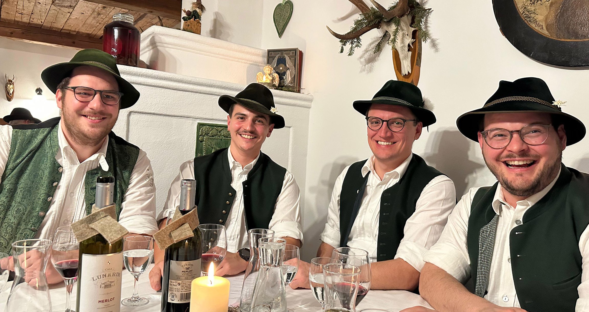 Vier Männer in Tracht mit Hüten an Tisch sitzend
