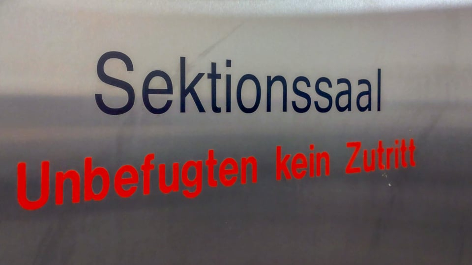 Ein Schild mit der Aufschrift Sektionssaal in schwarz und Unbefugten kein Zutritt in rot