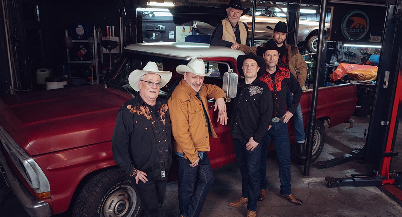 Foto einer Gruppe von Männern in einer Autowerkstatt, die alle Cowboyhüte tragen