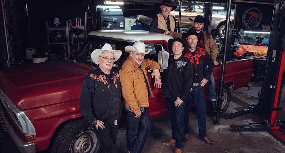 Foto einer Gruppe von Männern in einer Autowerkstatt, die alle Cowboyhüte tragen