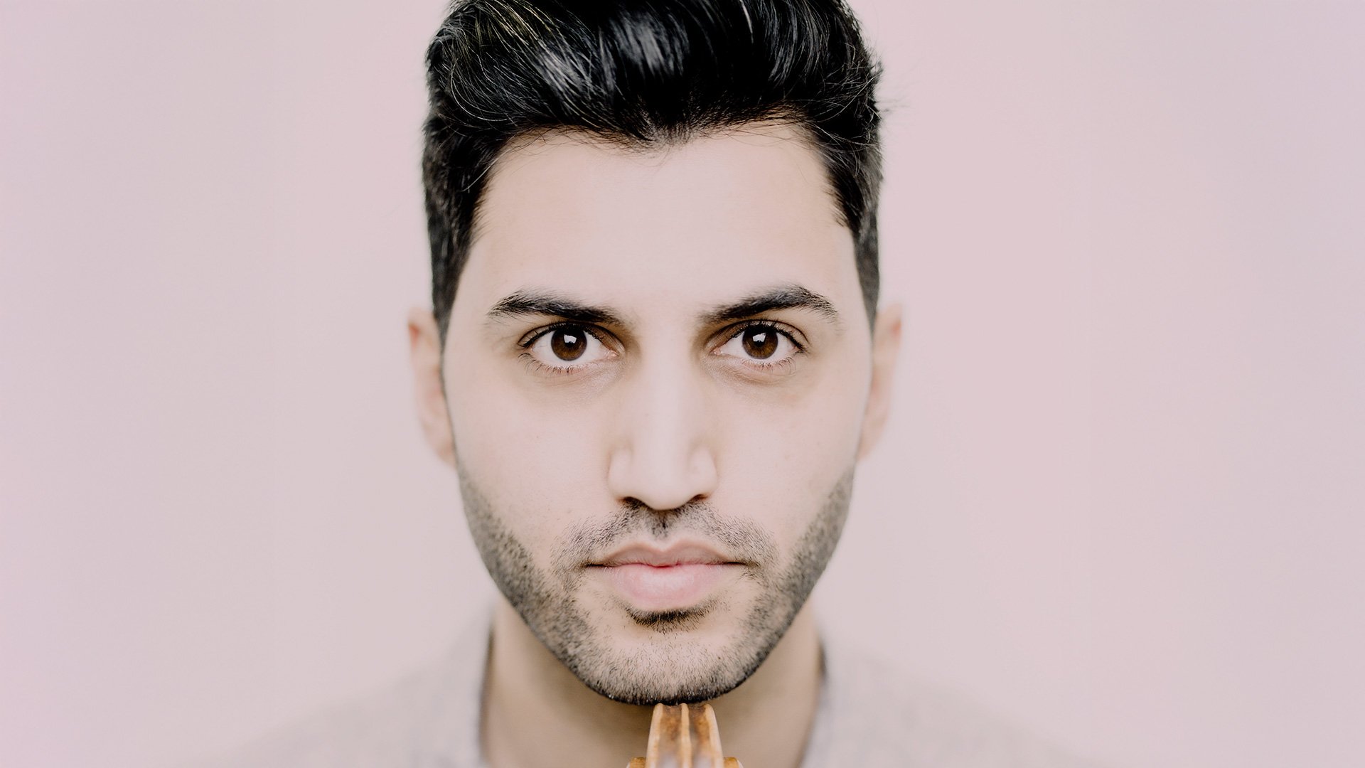 Porträt von Kian Soltani, Cellist, mit seinem Instrument vor hellem Hintergrund.