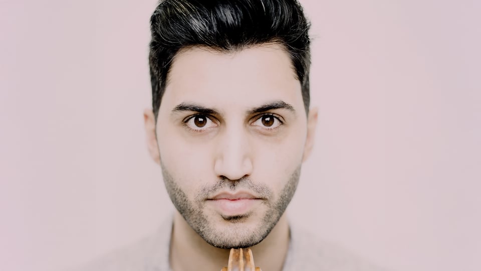 Porträt von Kian Soltani, Cellist, mit seinem Instrument vor hellem Hintergrund.