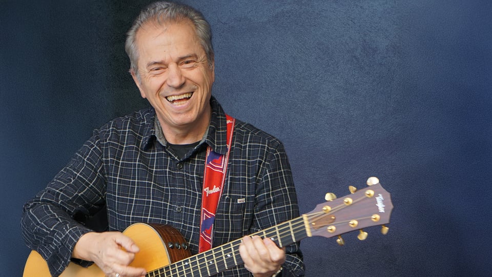 Der Künstler mit Gitarre vor blauem Hintergrund