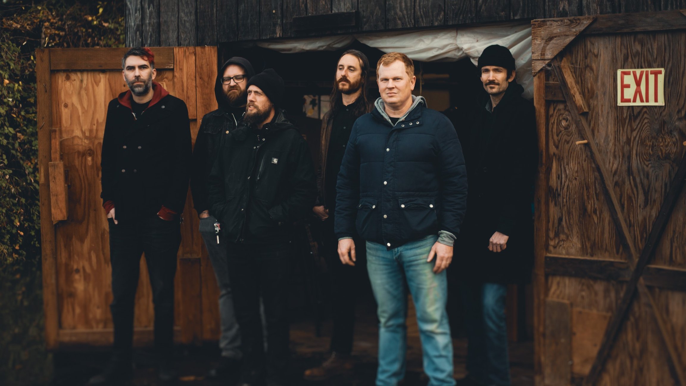 Die Band vor einer Holzhütte stehend