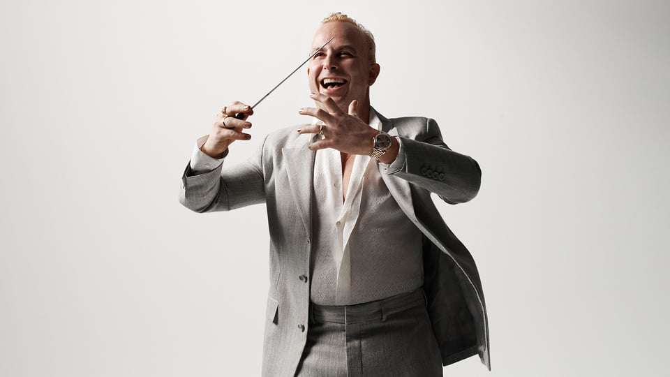 Pressefoto von Yannick Nézet-Séguin, Dirigent mit Taktstock, vor hellem Hintergrund.