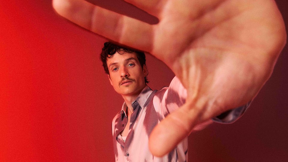 Foto für das Event von PaulWetz mit dem Künstler und der Handfläche im Vordergrund vor rotem Hintergrund.