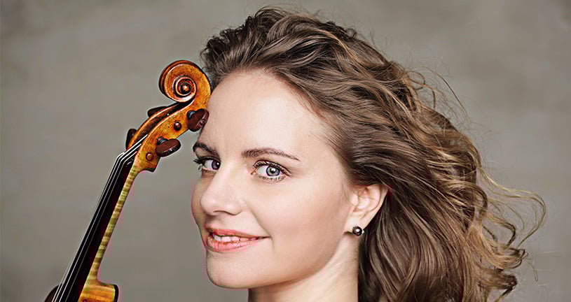 Julia Fischer vor grauem Hintergrund mit Instrument 