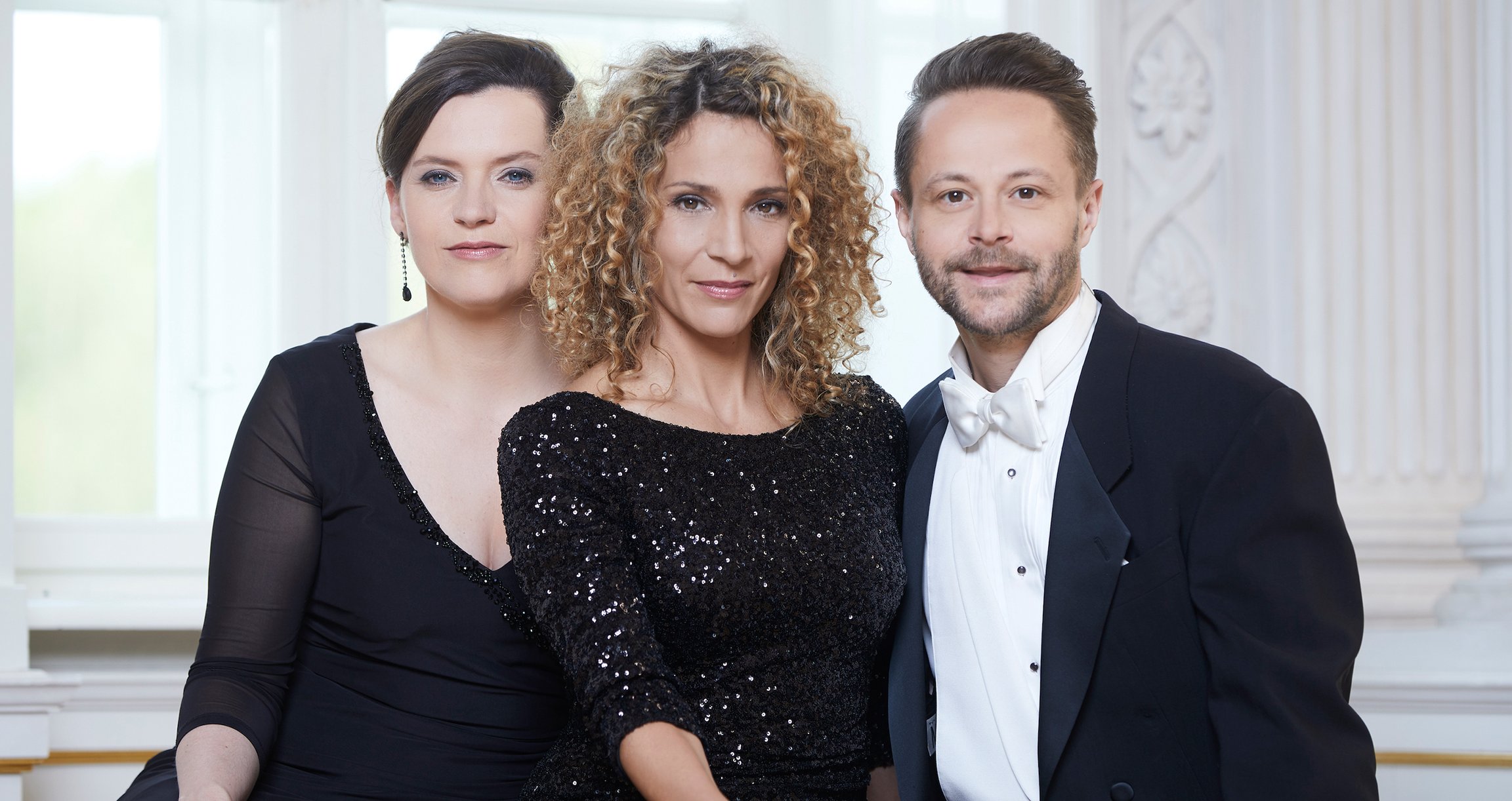 zwei elegant gekleidete Frauen und ein Mann