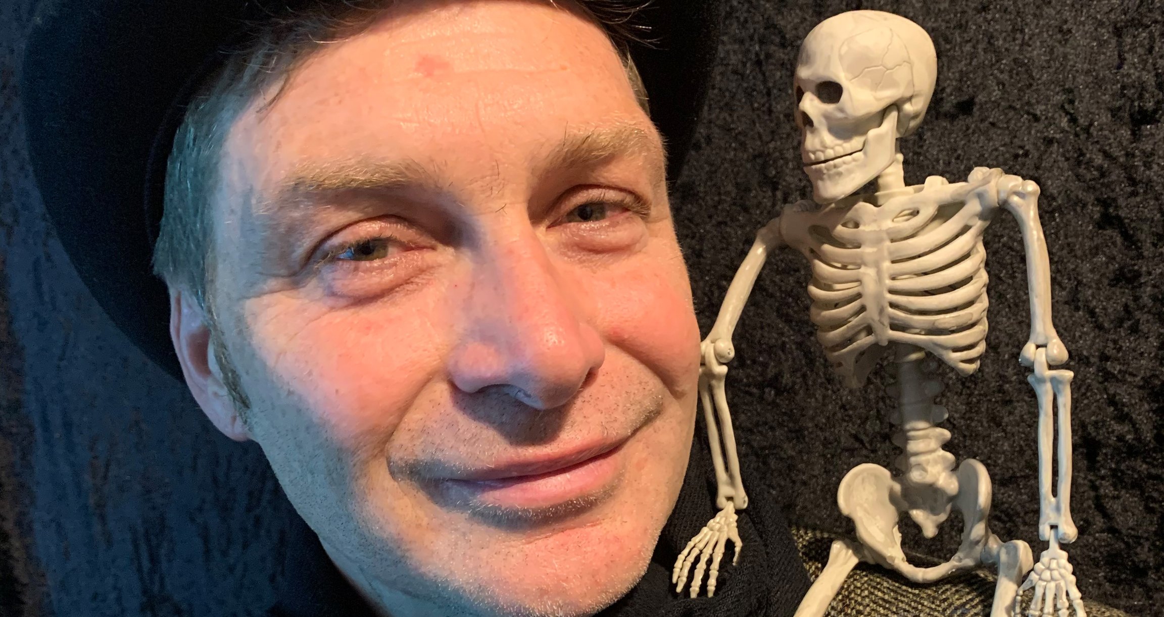 Mann mit Hut und Skelett auf der Schulter