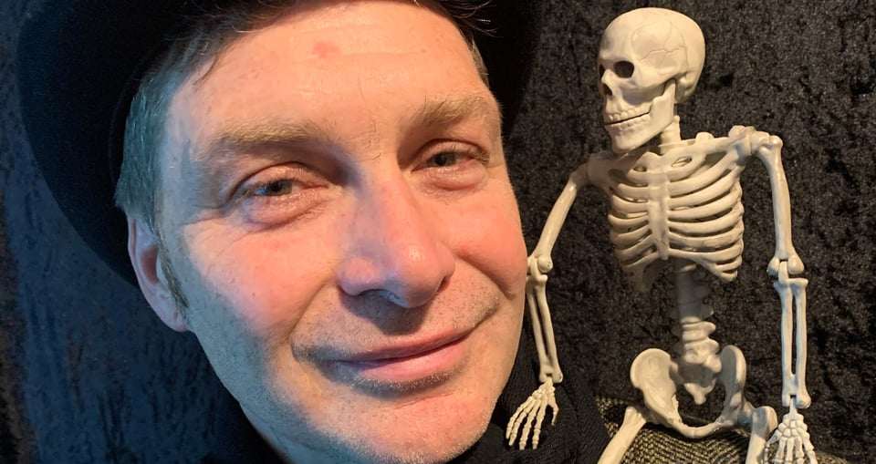 Mann mit Hut und Skelett auf der Schulter