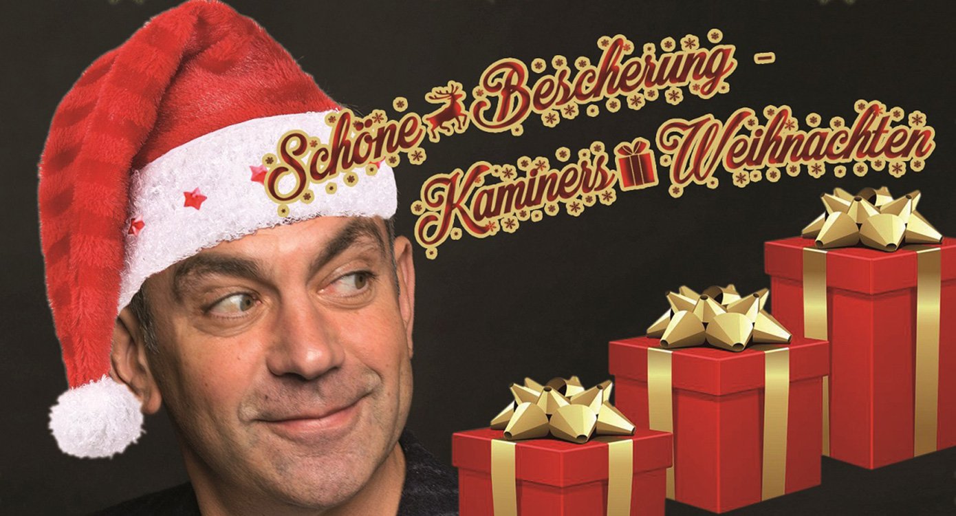 Mann mit roter Zipfelmütze mit Aufschrift und Geschenkschachteln vor schwarzem Hintergrund