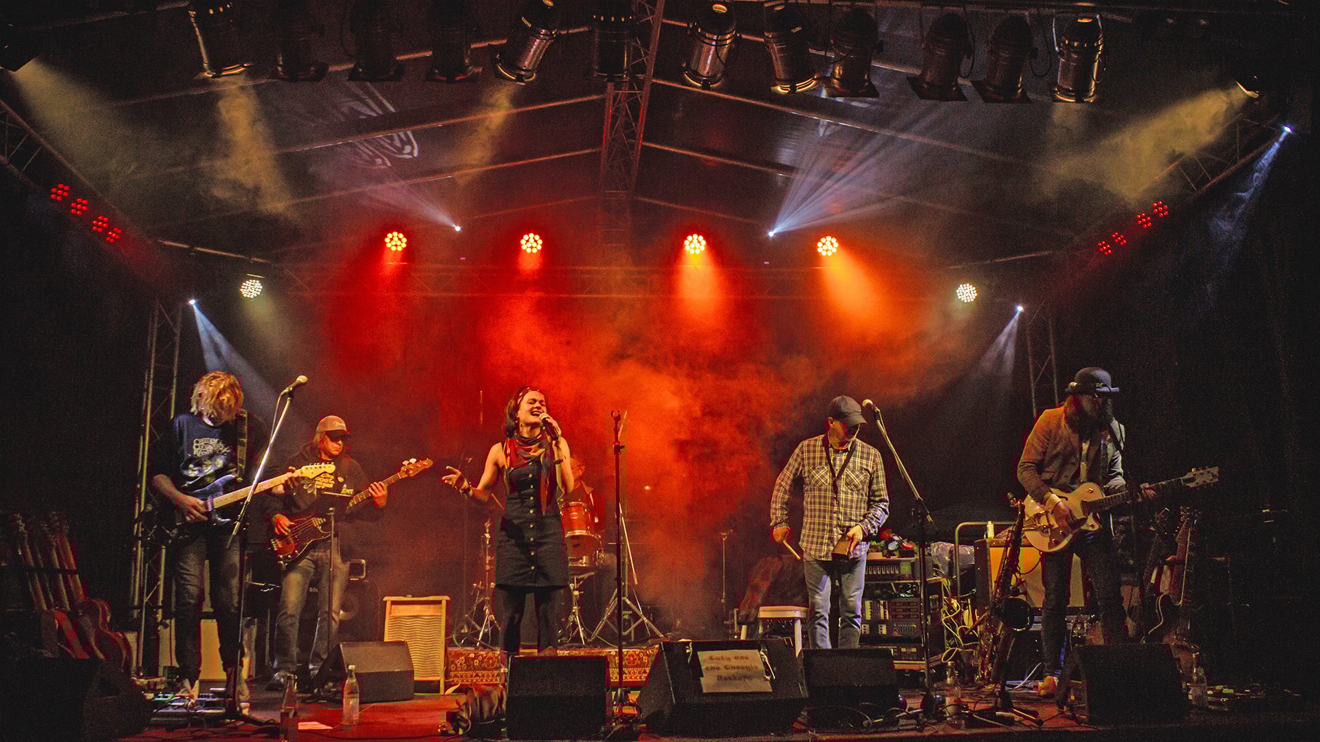 Foto für die Veranstaltung Caty and the Choogle Rockers, mit der Band auf einer Bühne mit roten Lichtern.