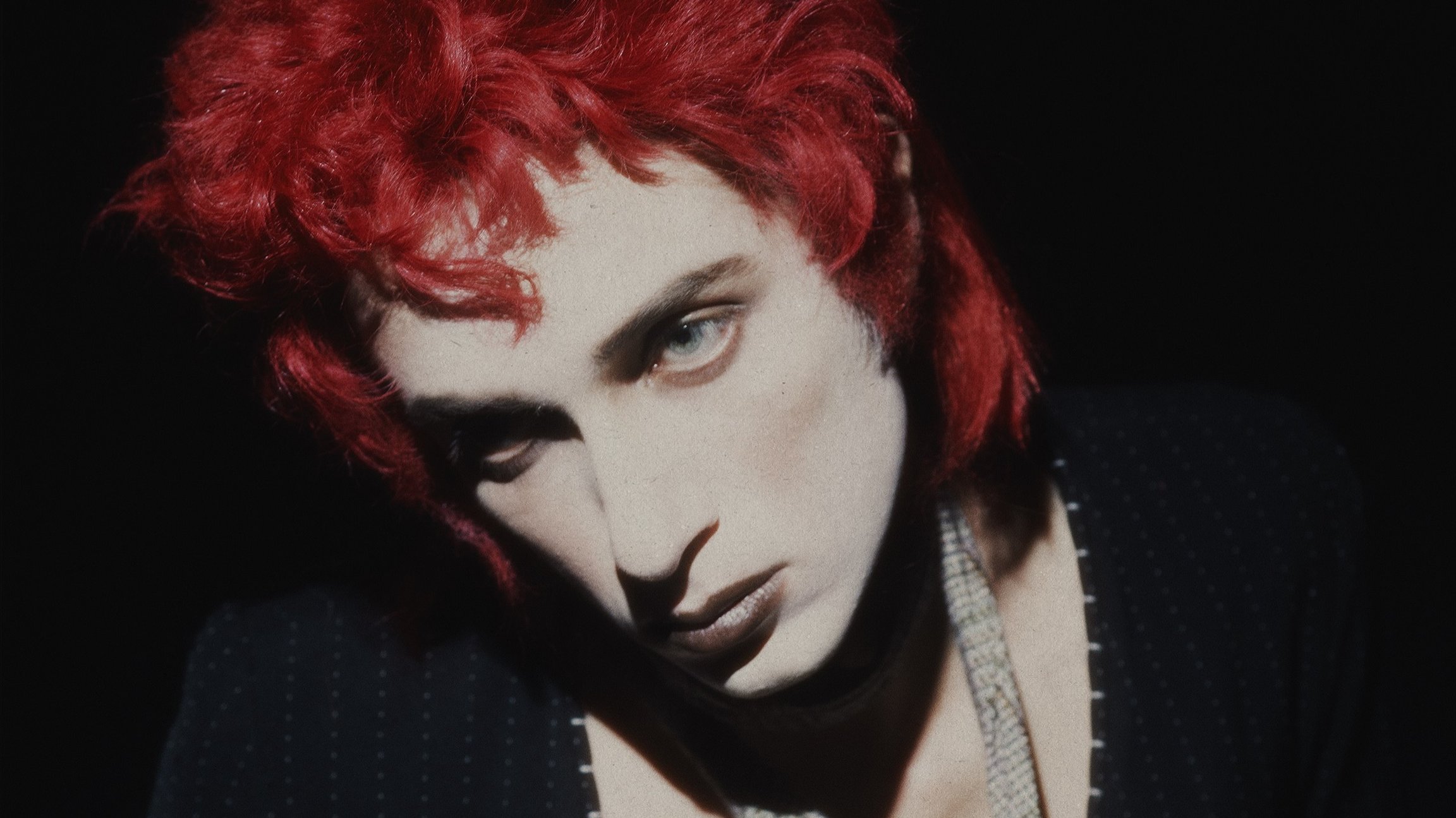 Foto vom Gesicht einer Frau mit roten Haaren vor schwarzem Hintergrund