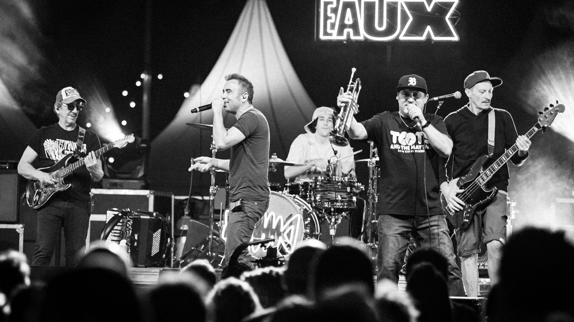 Schwarz‑Weiß‑Foto für das Les‑Barbeaux‑Event, mit der ganzen Band auf der Bühne, mit Mikrofonen und Instrumenten