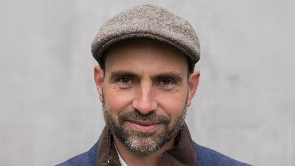 Foto des Künstlers Aurel Bereuter mit einer Baskenmütze vor hellem Hintergrund