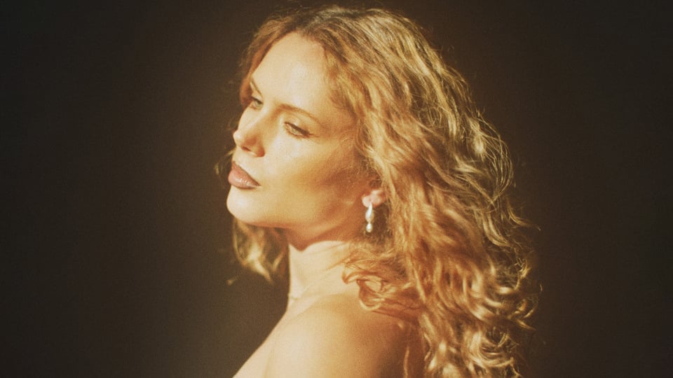 Ein Foto von Eli Preiss, die seitlich zur Kamera steht und nach unten guckt mit einem leuchtenden Filter.