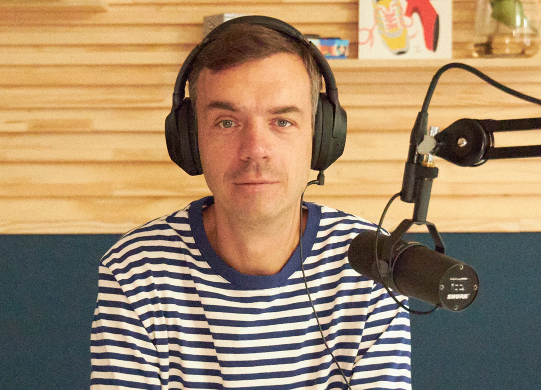 Mann in gestreiftem Shirt mit Kopfhörer vor Mikofon