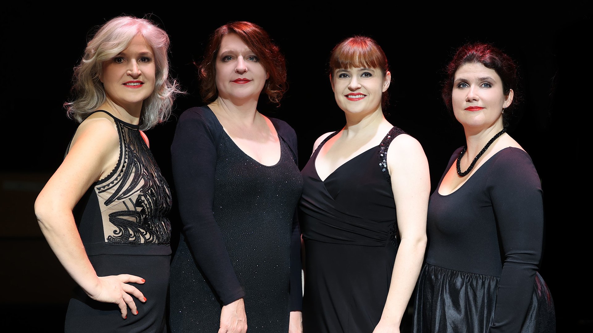 Foto für die Veranstaltung von Vokal Total – Aquabella, mit vier Frauen in Schwarz gekleidet vor schwarzem Hintergrund