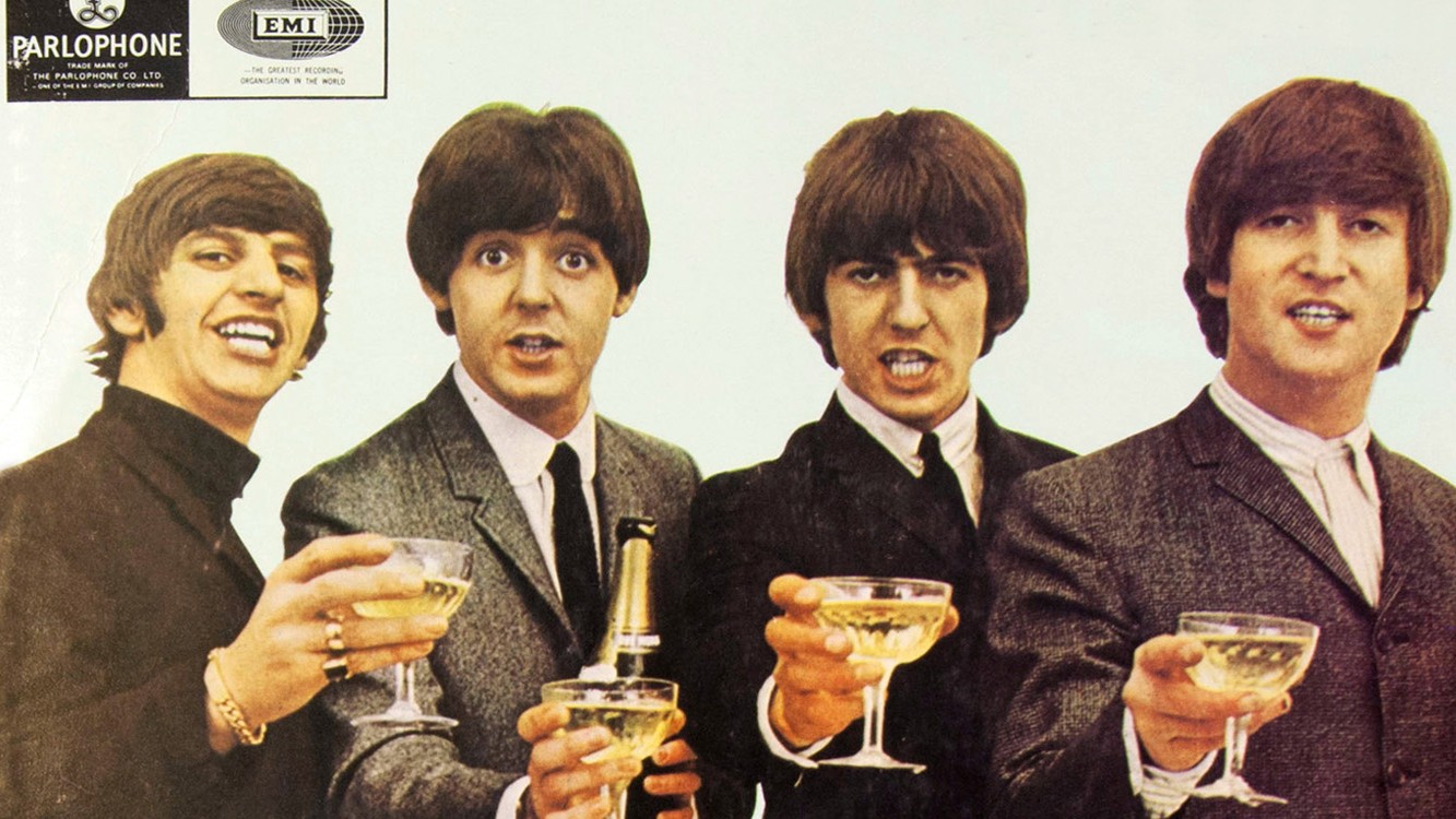 Ein Foto der Beatles in dunklen Anzügen mit Gläsern in den Händen 