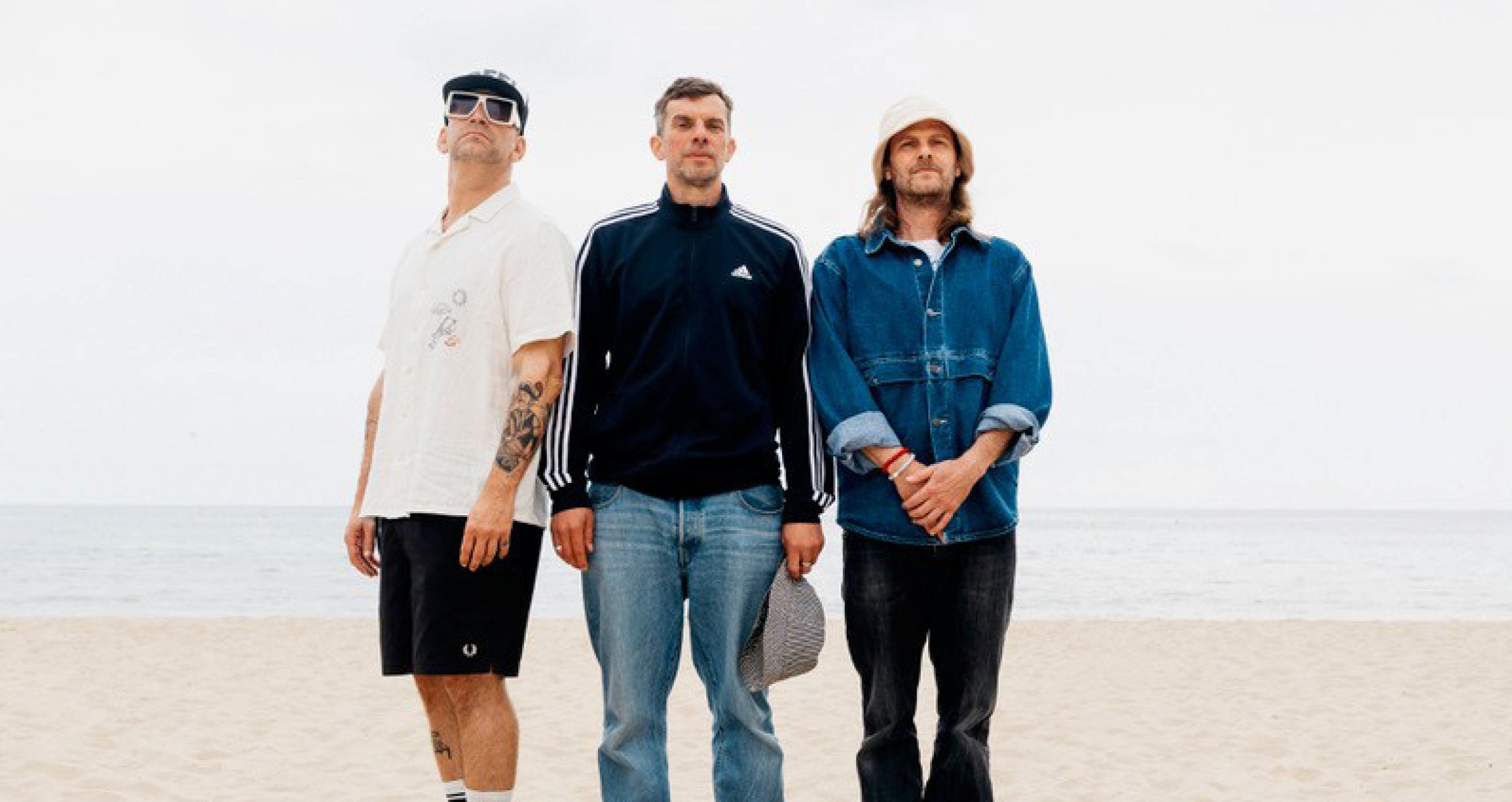 Foto für die Veranstaltung SPORTFREUNDE STILLER mit den drei Künstlern vor einem Strandhintergrund