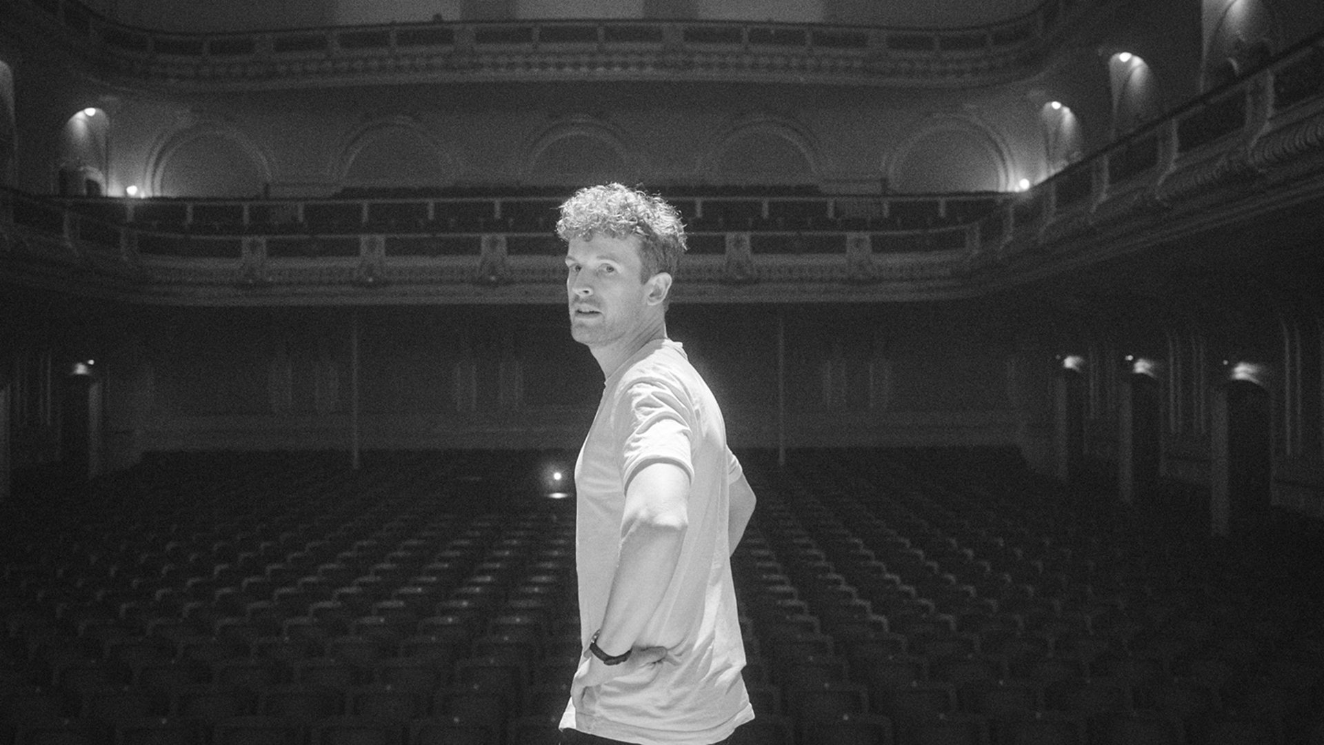 schwarz weiss Bild des Künstlers vor der Kulisse eines Theaters